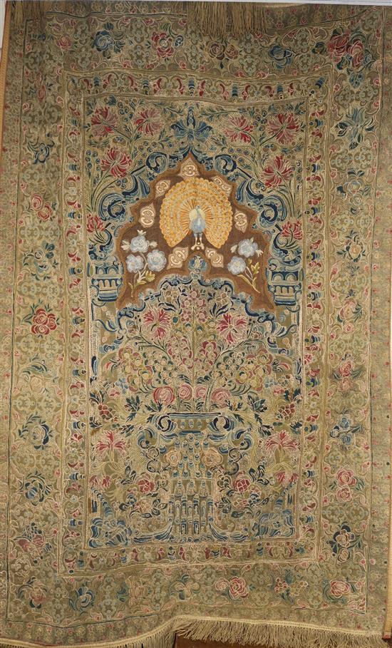 An Indian silk wall hanging, probably Iranian, featuring a peacock under an arch H.180cm W.115cm.